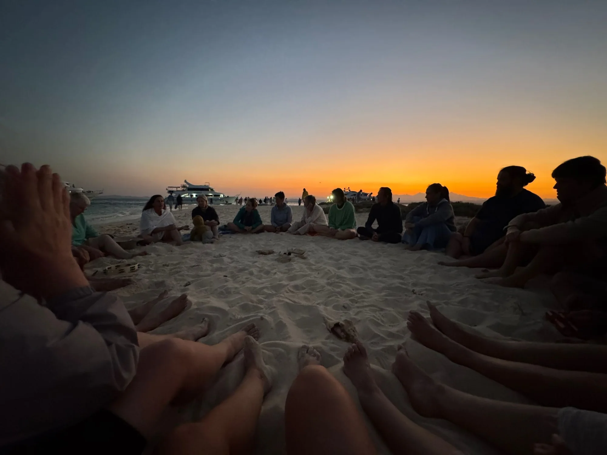 The group in a circle on a sandbank at sunset